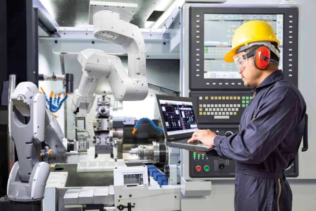 Engineer working on a machine and analysing data in Laptop